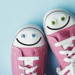 Pink canvas shoes with happy faces on blue background