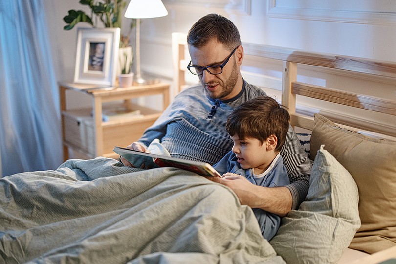 Man and child reading a book at bedtime